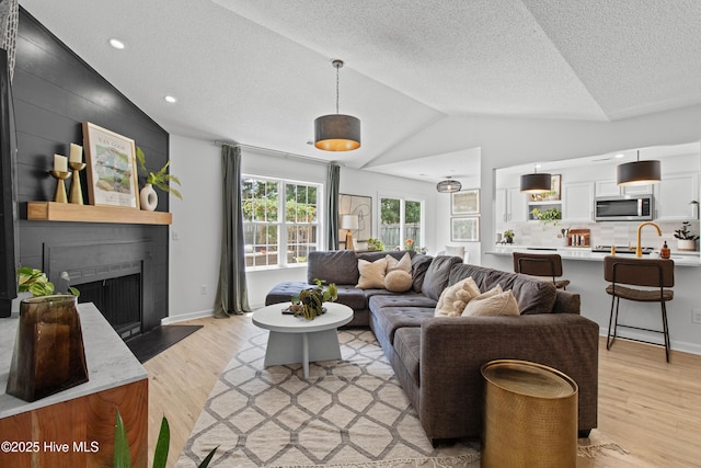 415 Point View Ct, Wilmington, NC 28411 - living room with lofted ceiling, light wood-style flooring, a fireplace, a textured ceiling, and recessed lighting