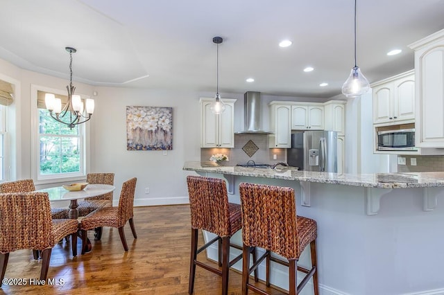 4010 Sienna Trl, New Bern, NC 28562 - kitchen featuring wall chimney range hood, stainless steel appliances, a breakfast bar area, baseboards, and dark wood finished floors