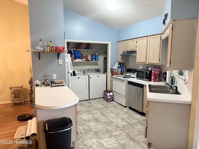 kitchen featuring under cabinet range hood, washer and dryer, a sink, vaulted ceiling, and white appliances