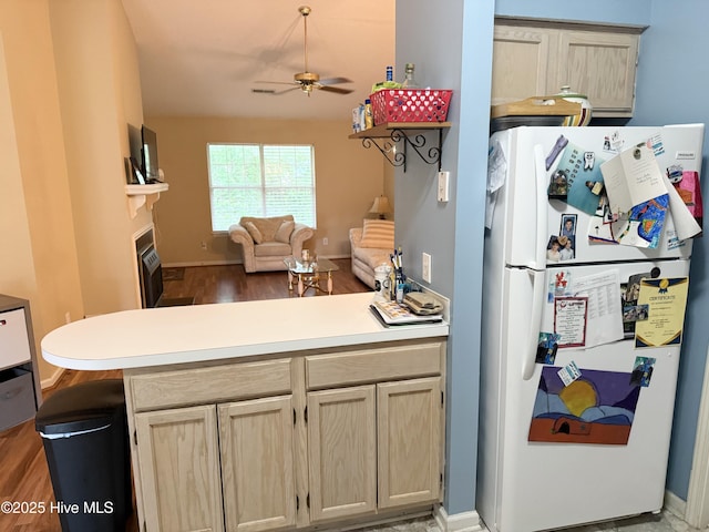 kitchen with freestanding refrigerator, ceiling fan, open floor plan, wood finished floors, and a peninsula