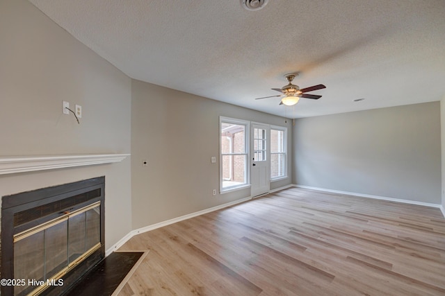 4941 Marlin Ct, Wilmington, NC 28403 - unfurnished living room featuring a textured ceiling, a fireplace with flush hearth, light wood-type flooring, a ceiling fan, and baseboards