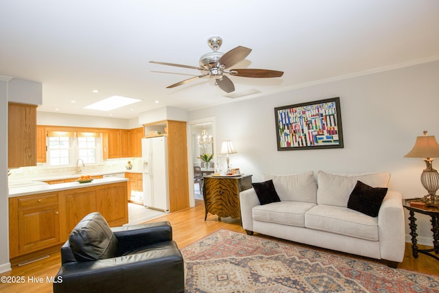 7 Saddle Pl, Pinehurst, NC 28374 - living area featuring a skylight, light wood-type flooring, ceiling fan, a chandelier, and crown molding