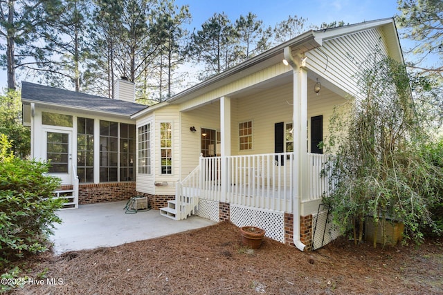 3665 Willow Lake Dr SE, Southport, NC 28461 - view of front of house featuring a chimney, a sunroom, and a patio