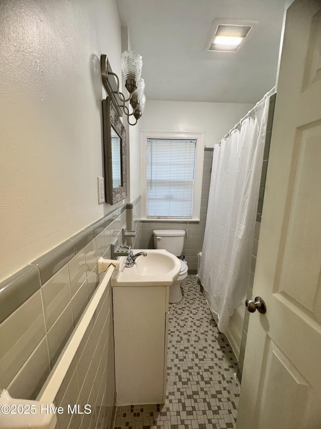 1305 Westwood Ave W, Wilson, NC 27893 - full bath featuring tile walls, toilet, vanity, tile patterned floors, and wainscoting