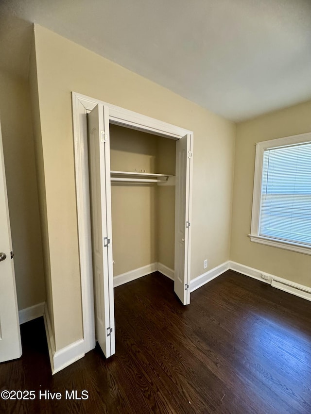 1305 Westwood Ave W, Wilson, NC 27893 - unfurnished bedroom featuring wood finished floors, baseboards, a closet, and a baseboard heating unit