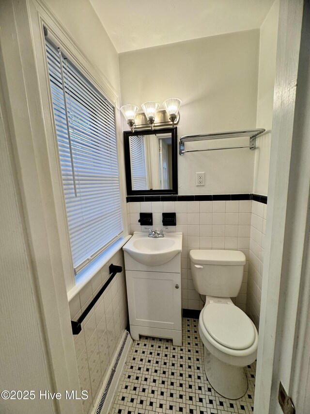 1305 Westwood Ave W, Wilson, NC 27893 - bathroom with tile walls, toilet, vanity, a chandelier, and wainscoting