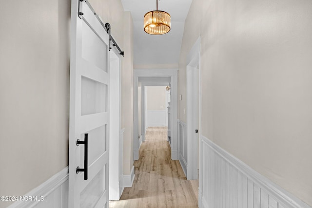 107 Rockingham Rd, Rockingham, NC 28379 - corridor with a barn door, a wainscoted wall, light wood-type flooring, and a chandelier
