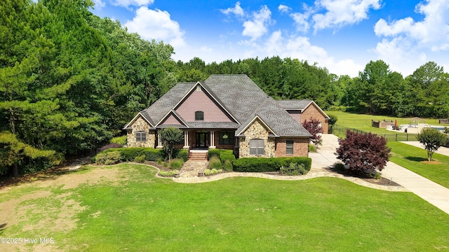207 Hooping Crane Ln, Goldsboro, NC 27530 - view of front facade featuring stone siding, a front yard, covered porch, and driveway