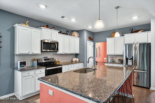 1114 Treyburn Ct NW, Calabash, NC 28467 - kitchen featuring appliances with stainless steel finishes, a sink, dark wood finished floors, tasteful backsplash, and white cabinetry
