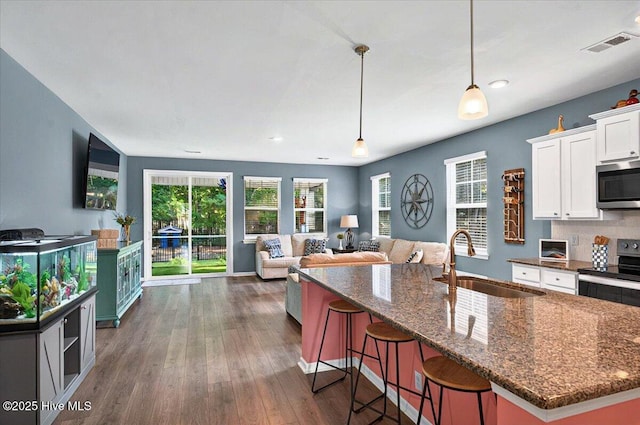 1114 Treyburn Ct NW, Calabash, NC 28467 - kitchen with stainless steel appliances, a sink, white cabinetry, dark stone countertops, and dark wood finished floors