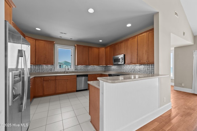 905 N Anderson Blvd, Topsail Beach, NC 28445 - kitchen with appliances with stainless steel finishes, a peninsula, a sink, light countertops, and brown cabinetry