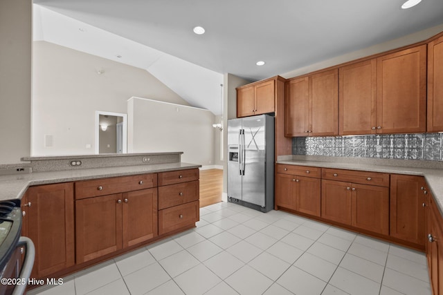 905 N Anderson Blvd, Topsail Beach, NC 28445 - kitchen with stainless steel refrigerator with ice dispenser, brown cabinetry, range, tasteful backsplash, and lofted ceiling