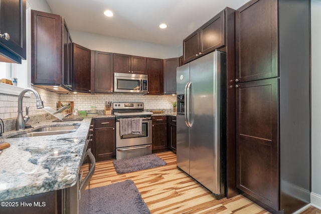 106 NW 8th St, Oak Island, NC 28465 - kitchen with appliances with stainless steel finishes, a sink, light wood-style floors, light stone countertops, and recessed lighting
