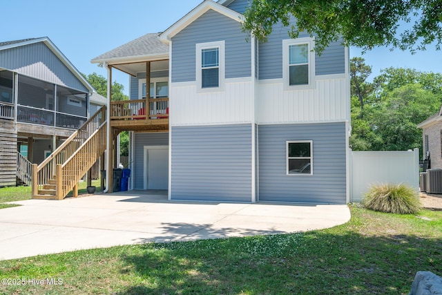 106 NW 8th St, Oak Island, NC 28465 - view of front of property with an attached garage, concrete driveway, stairs, a sunroom, and roof with shingles