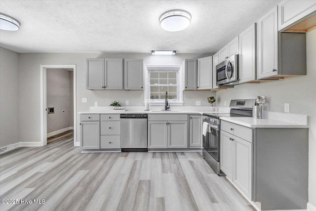 1102 Elanor Ave, Goldsboro, NC 27530 - kitchen featuring stainless steel appliances, gray cabinets, a textured ceiling, light wood-style floors, and light countertops
