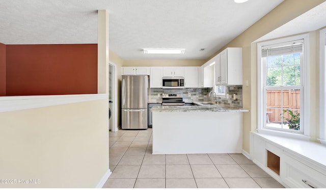 416 Point View Ct, Wilmington, NC 28411 - kitchen featuring appliances with stainless steel finishes, a sink, light tile patterned floors, white cabinetry, and backsplash