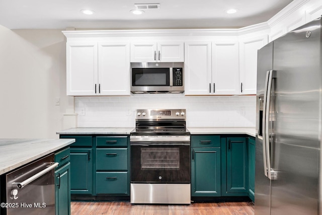 562 Anchor Way, Kure Beach, NC 28449 - kitchen with stainless steel appliances, white cabinets, green cabinets, light wood-style flooring, and decorative backsplash