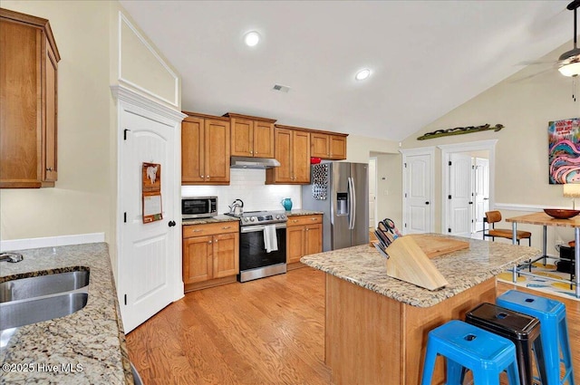 2121 Maple Leaf Dr, Southport, NC 28461 - kitchen featuring stainless steel appliances, a sink, a kitchen breakfast bar, light wood finished floors, and light stone counters