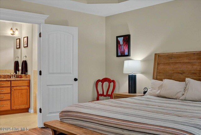 2121 Maple Leaf Dr, Southport, NC 28461 - bedroom with ensuite bath, light tile patterned floors, and a sink