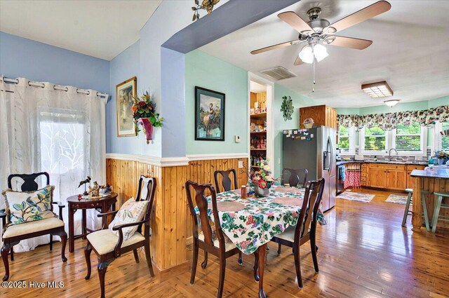 245 Green Bay Rd NW, Ocean Isle Beach, NC 28469 - dining room featuring a wainscoted wall, a ceiling fan, light wood-style floors, and wood walls