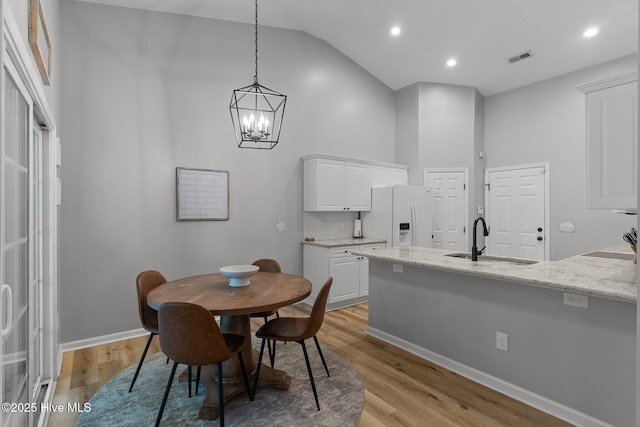 817 Glenarthur Dr, Wilmington, NC 28412 - dining area featuring a chandelier, light wood-style floors, baseboards, high vaulted ceiling, and recessed lighting