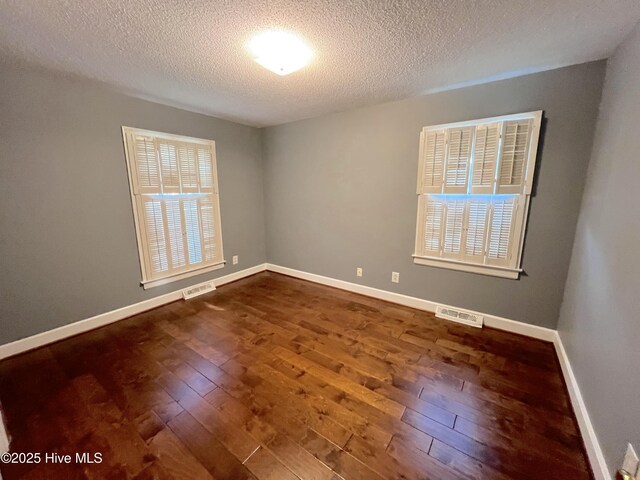 1811 Hermitage Rd NW, Wilson, NC 27896 - spare room featuring dark wood-style floors, a textured ceiling, and baseboards