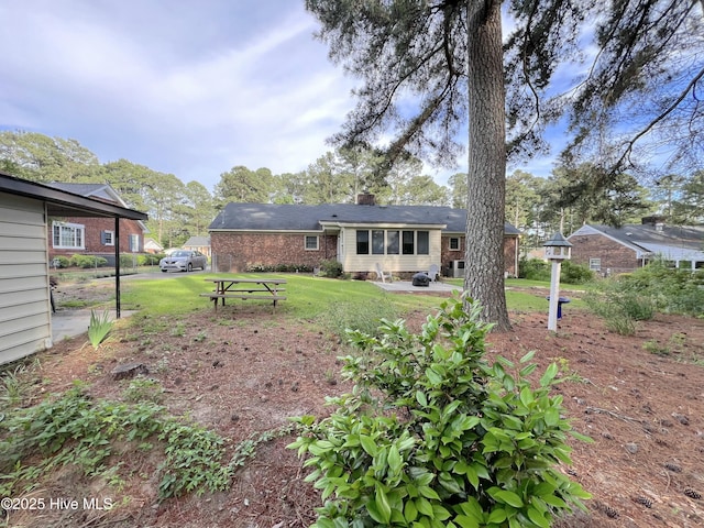 1811 Hermitage Rd NW, Wilson, NC 27896 - rear view of house with brick siding, a chimney, a yard, and a patio