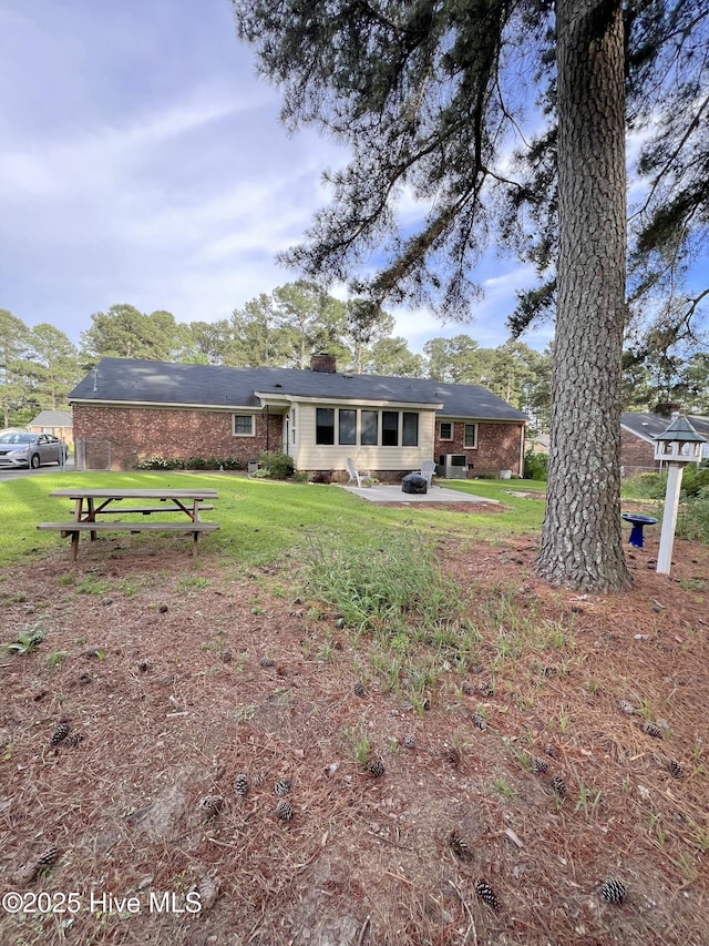 1811 Hermitage Rd NW, Wilson, NC 27896 - rear view of property with a yard, a patio area, a chimney, and brick siding