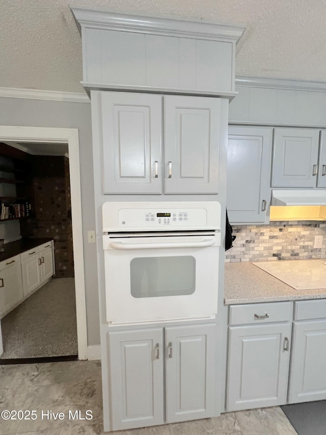 1811 Hermitage Rd NW, Wilson, NC 27896 - kitchen featuring oven, crown molding, decorative backsplash, light countertops, and a textured ceiling