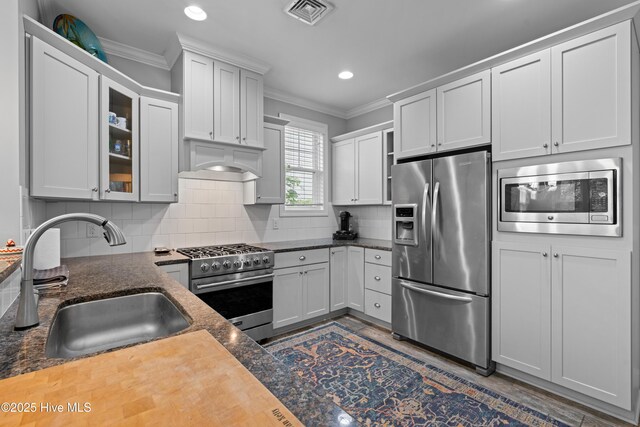 117 Bimini Townes Ln, Carolina Beach, NC 28428 - kitchen with appliances with stainless steel finishes, a sink, ornamental molding, backsplash, and glass insert cabinets