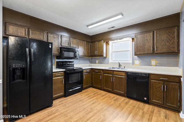 716 Shadowridge Rd, Jacksonville, NC 28546 - kitchen featuring black appliances, a sink, light countertops, light wood-type flooring, and dark brown cabinets