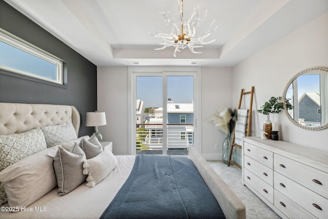 221 Georgia Ave, Carolina Beach, NC 28428 - bedroom featuring a chandelier, access to exterior, a tray ceiling, light colored carpet, and baseboards