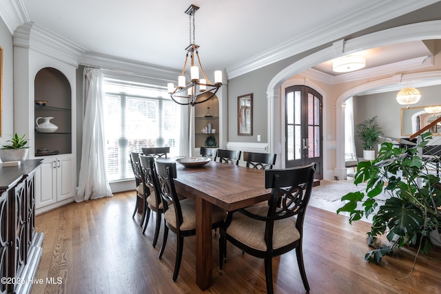 509 Westminster Cir, Greenville, NC 27858 - dining area with a chandelier, arched walkways, crown molding, light wood-style floors, and built in shelves