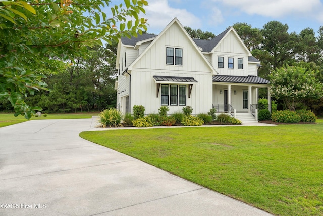 204 N Sea Lily Ct, Hampstead, NC 28443 - view of front facade with a standing seam roof, a porch, board and batten siding, concrete driveway, and a front yard