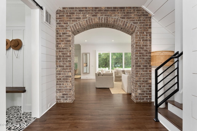 204 N Sea Lily Ct, Hampstead, NC 28443 - hall featuring wood finished floors, stairway, arched walkways, a barn door, and brick wall