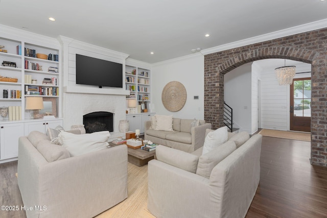 204 N Sea Lily Ct, Hampstead, NC 28443 - living area featuring wood finished floors, crown molding, a brick fireplace, arched walkways, and built in shelves