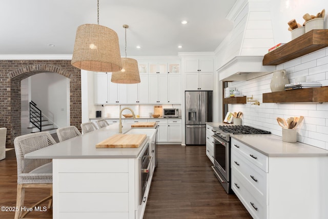204 N Sea Lily Ct, Hampstead, NC 28443 - kitchen featuring stainless steel appliances, open shelves, a breakfast bar, tasteful backsplash, and dark wood finished floors