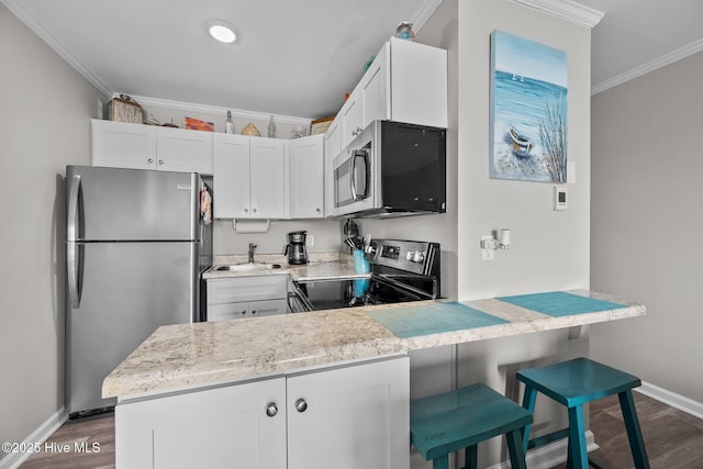 kitchen with appliances with stainless steel finishes, baseboards, crown molding, dark wood-style flooring, and a peninsula