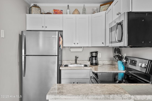 kitchen with appliances with stainless steel finishes, a sink, light countertops, white cabinetry, and crown molding
