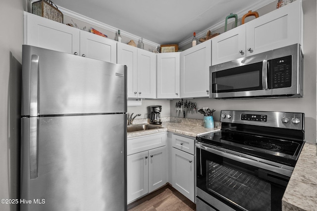kitchen featuring stainless steel appliances, light countertops, a sink, and white cabinetry