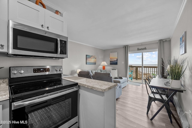 kitchen featuring appliances with stainless steel finishes, light countertops, ornamental molding, white cabinets, and light wood finished floors