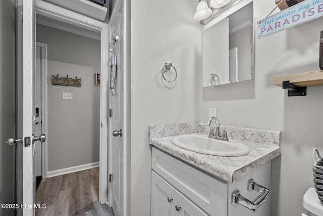 bathroom with wood finished floors, vanity, and baseboards