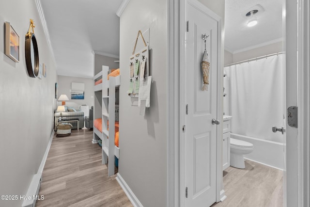 hall with ornamental molding, light wood-style floors, and baseboards