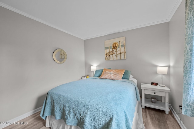 bedroom featuring ornamental molding, wood finished floors, and baseboards