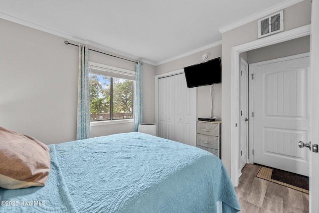 bedroom with ornamental molding, wood finished floors, and a closet