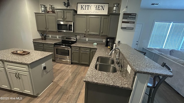 87 Strut Way, Rocky Point, NC 28457 - kitchen with stainless steel appliances, a sink, light wood-style floors, a breakfast bar, and backsplash