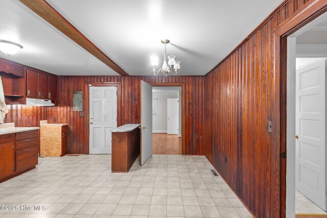1704 Charlotte Ave, Kinston, NC 28501 - kitchen with wooden walls, a chandelier, light countertops, under cabinet range hood, and pendant lighting
