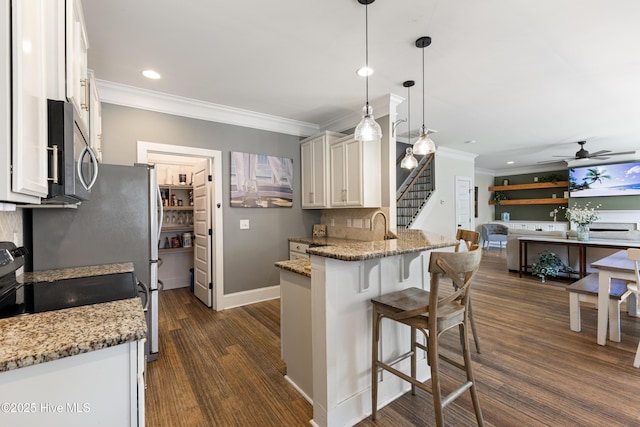 157 Heritage Way, Hampstead, NC 28443 - kitchen featuring stainless steel microwave, crown molding, recessed lighting, a kitchen bar, and light stone countertops