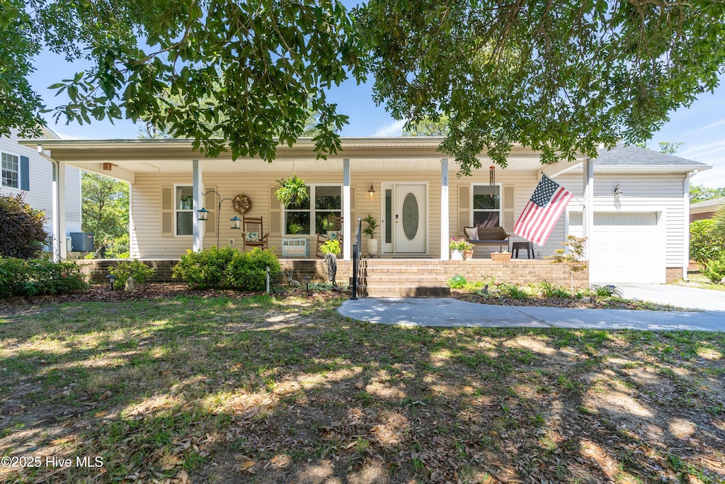 307 Norton St, Oak Island, NC 28465 - single story home featuring a porch, an attached garage, concrete driveway, and central AC