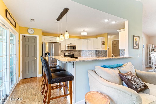 2 Beryl Cir, Pinehurst, NC 28374 - kitchen featuring appliances with stainless steel finishes, light stone countertops, backsplash, a kitchen bar, and recessed lighting